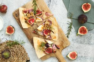 Auf dem Bild ist ein vegetarischer Flammkuchen mit Ziegenkäse und Feige zu sehen