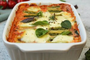 Zusehen ist ein Maultaschenauflauf mit Gemüse und Tomatensahnesoße mit Basilikumblättern als Zierde