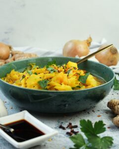 Hier ist ein vegetarischer Weißkohleintopf in einer blauen Schale und Sojasoße zu sehen