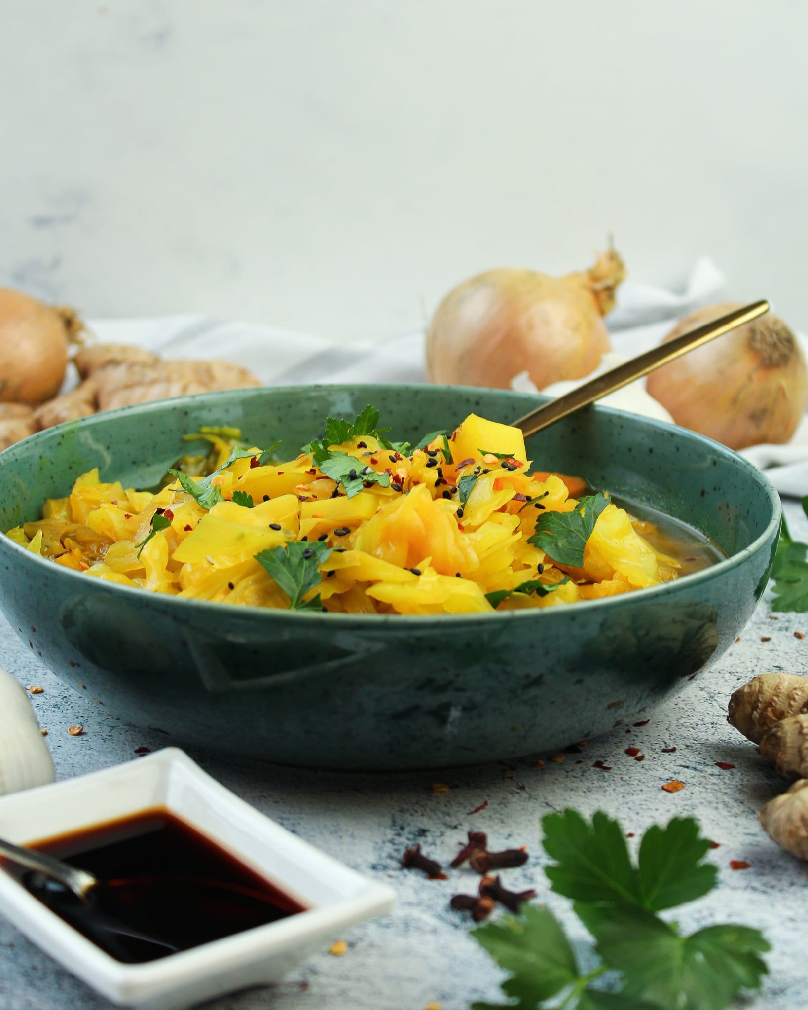 Hier ist ein vegetarischer Weißkohleintopf in einer blauen Schale und Sojasoße zu sehen