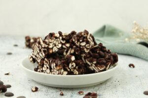 Zusehen sind Dinkelpuffer mit Zartbitterschokolade auf einem weißen Teller|Hier sieht man eine vegane Maronensuppe mit Kartoffel auf einem Tisch mit Kastanien