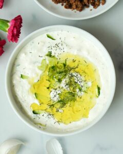 Hier ist ein Zaziki aus griechischem Joghurt zusehen|Auf dem Bild ist ein Tsatsiki mit Öl und Dilll zusehen