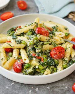 Auf dem Bild ist eine Pasta mit Spinat, Tomaten und Feta zusehen